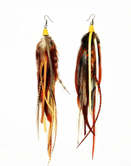 A pair of bohemian-style long earrings featuring a mix of natural brown feathers and hand-cut strips of metallic gold, bronze, and pewter leather. They are suspended from a gold-colored bronze bead cap and hypoallergenic ear wire, set against a white background, showcasing the earrings' layered and dynamic design.