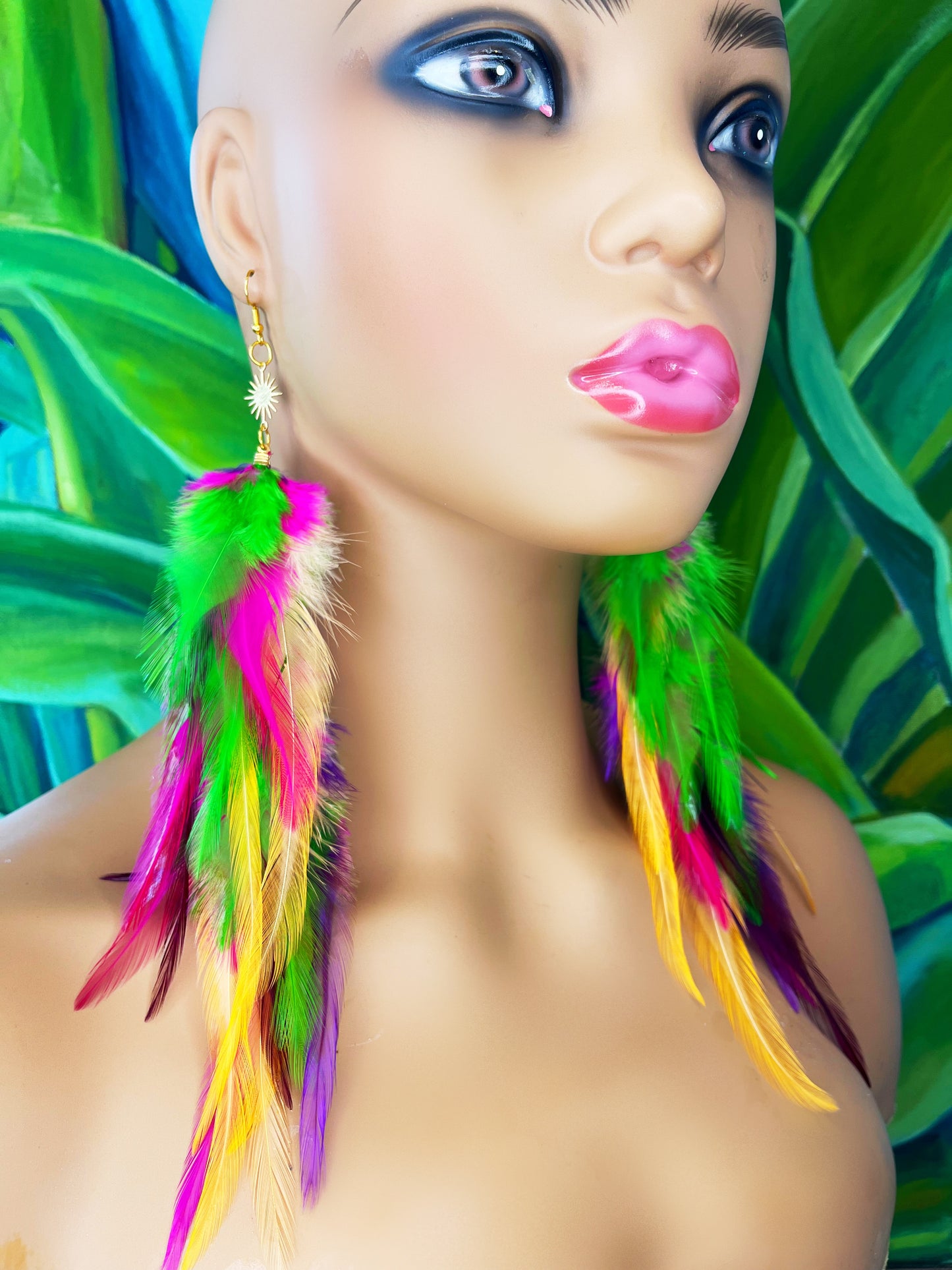 Long bohemian feather earrings in bright green, pink, purple and orange tones, worn on a mannequin. 