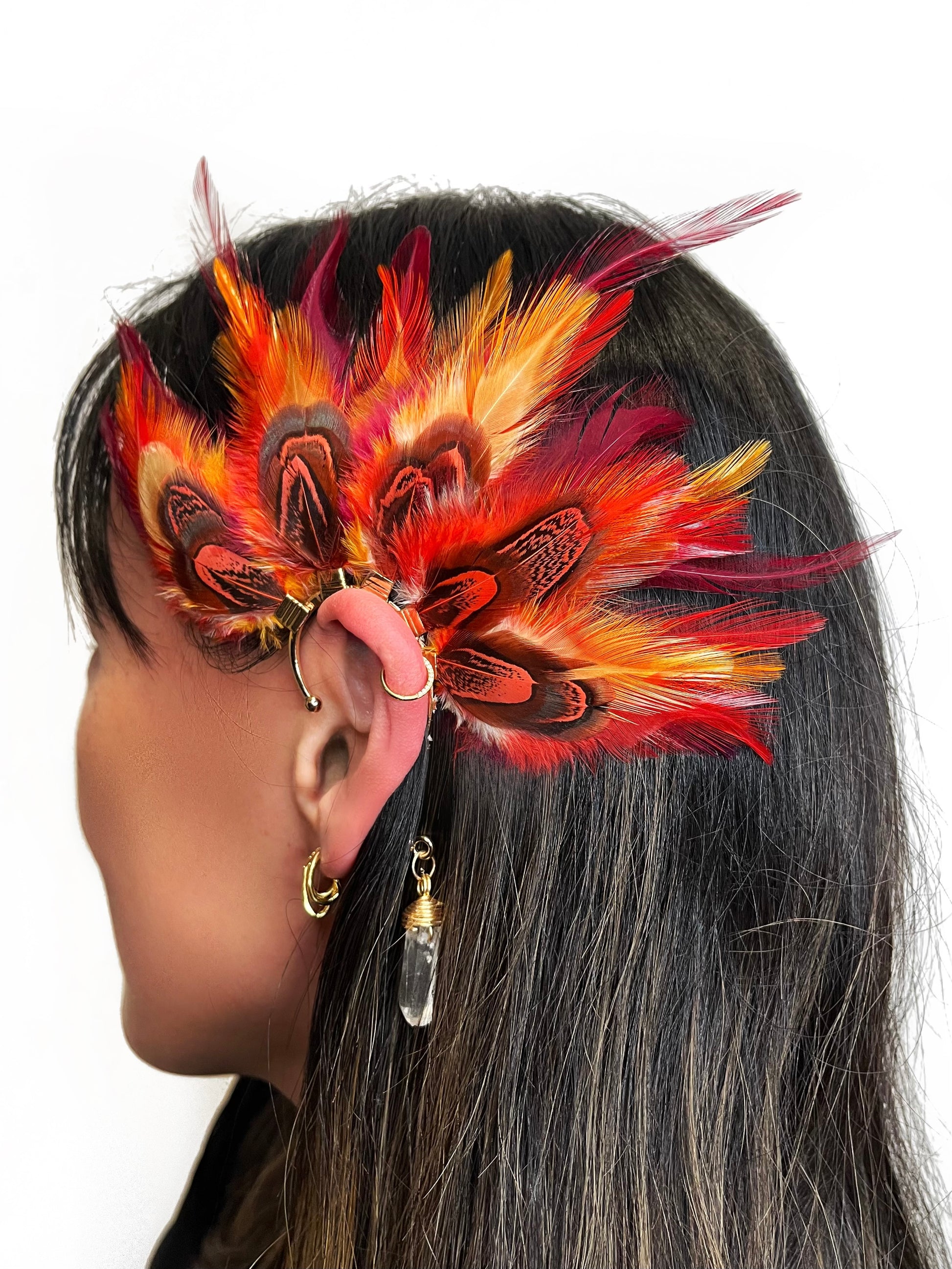 Rooster and pheasant ear cuff in vibrant red and orange colors, modeled on a woman. 