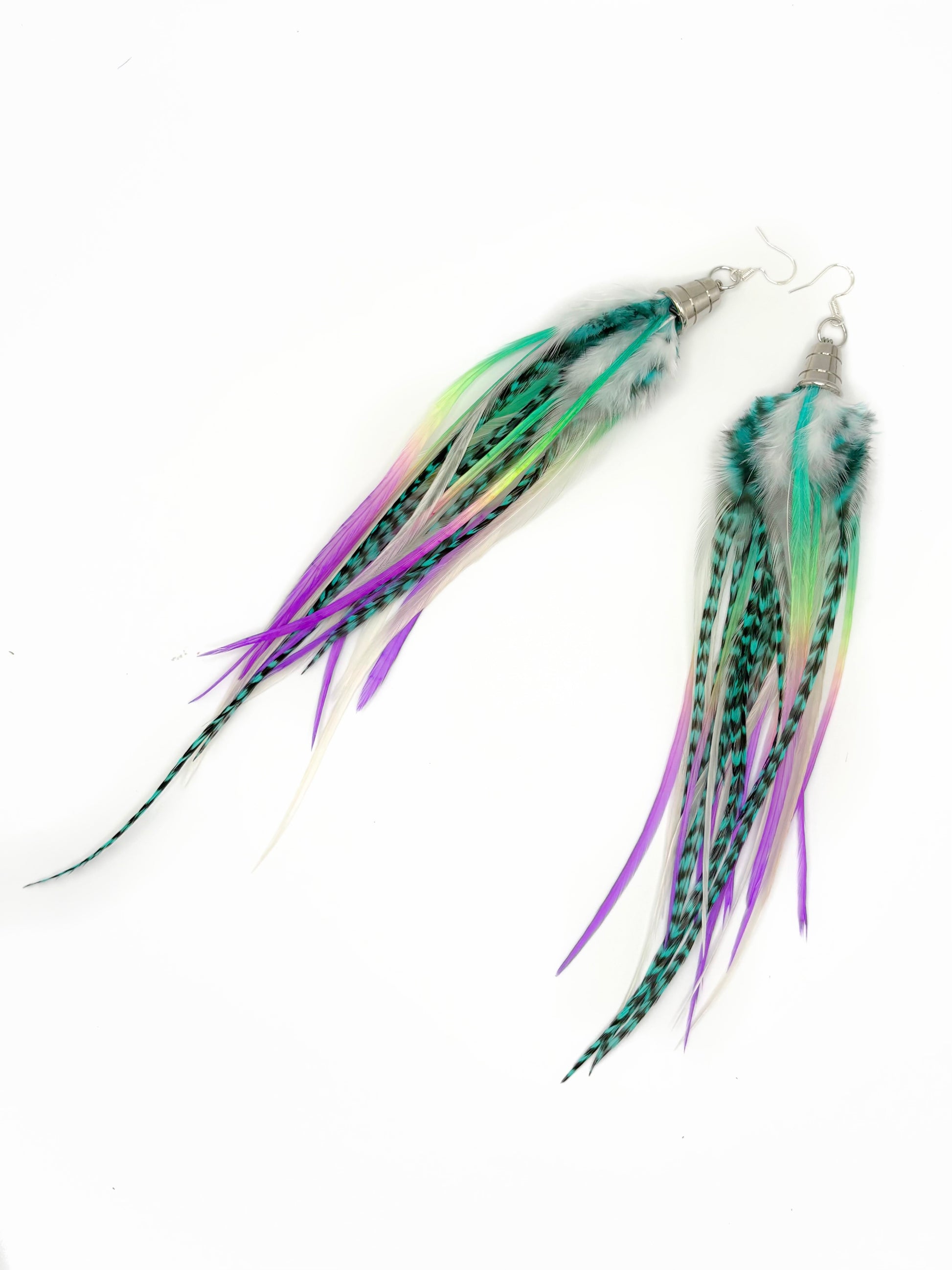 A pair of handmade dangle earrings featuring long, multi-colored feathers in shades of green, purple, and pink, attached to silver fishhook wires, shown against a plain white background.