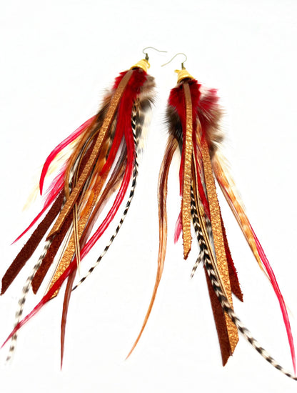 Long feather earrings in brown and deep red, with metallic bronze leather strips, hanging from a gold colored cap pendant.