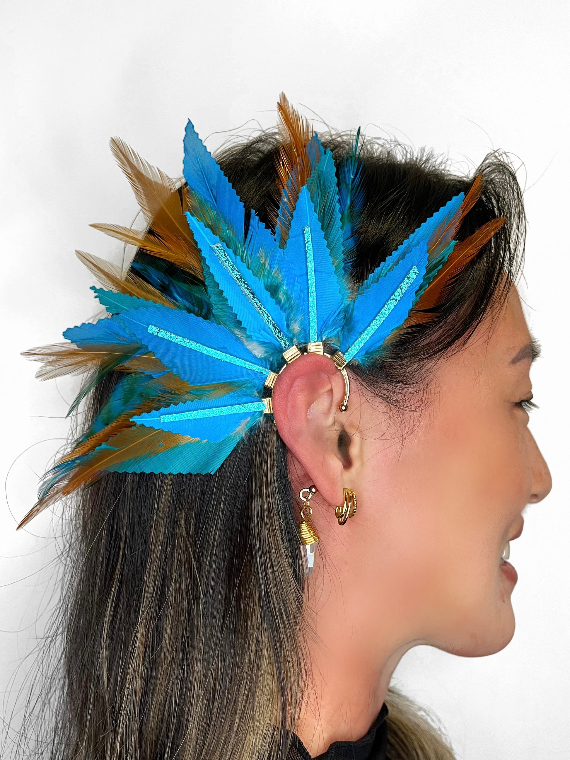 Turquoise blue and light brown feather ear cuff with blue leather accents and wire wrapped quartz dangle, modeled on a woman. 