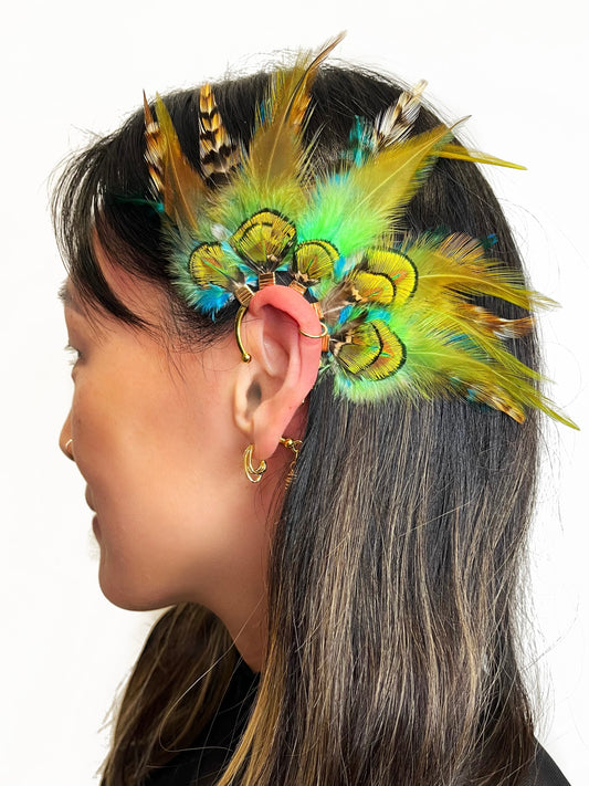 Green rooster and peacock feather ear cuff, modeled on a woman. 