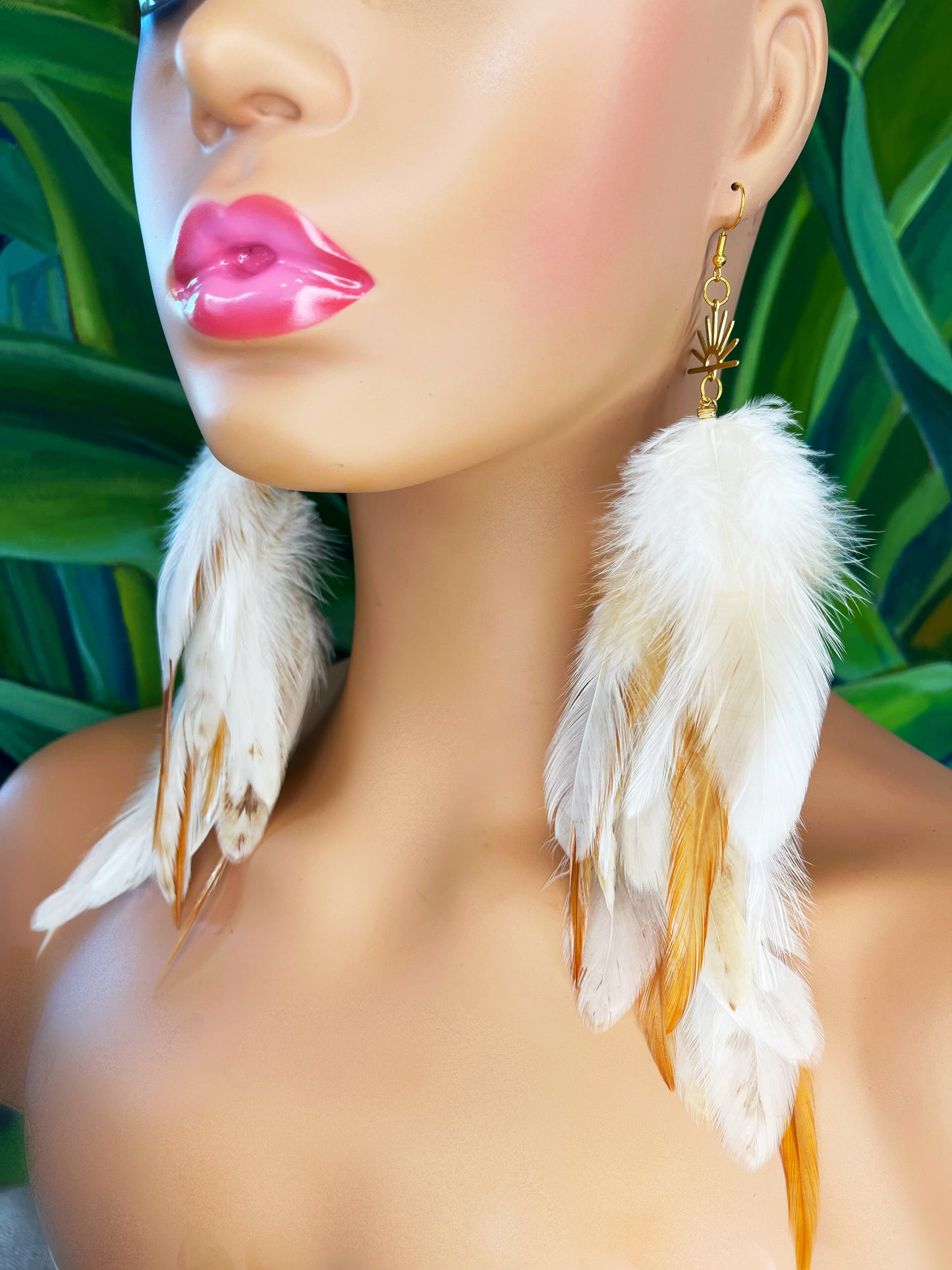 Long bohemian feather earrings in cream and beige tones, modeled on a mannequin. 