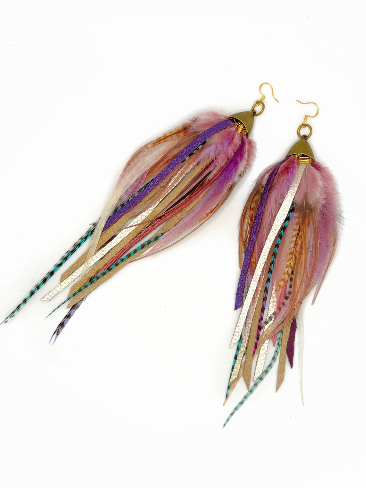 A pair of long, dangling feather earrings with gold-tone hooks and caps, featuring feathers in pink, purple, beige, brown, and white with some teal accents, set against a plain white background.