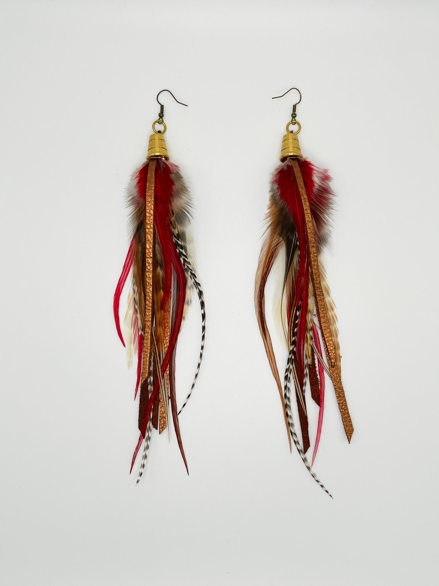 Long feather earrings in brown and deep red, with metallic bronze leather strips, hanging from a gold colored cap pendant.