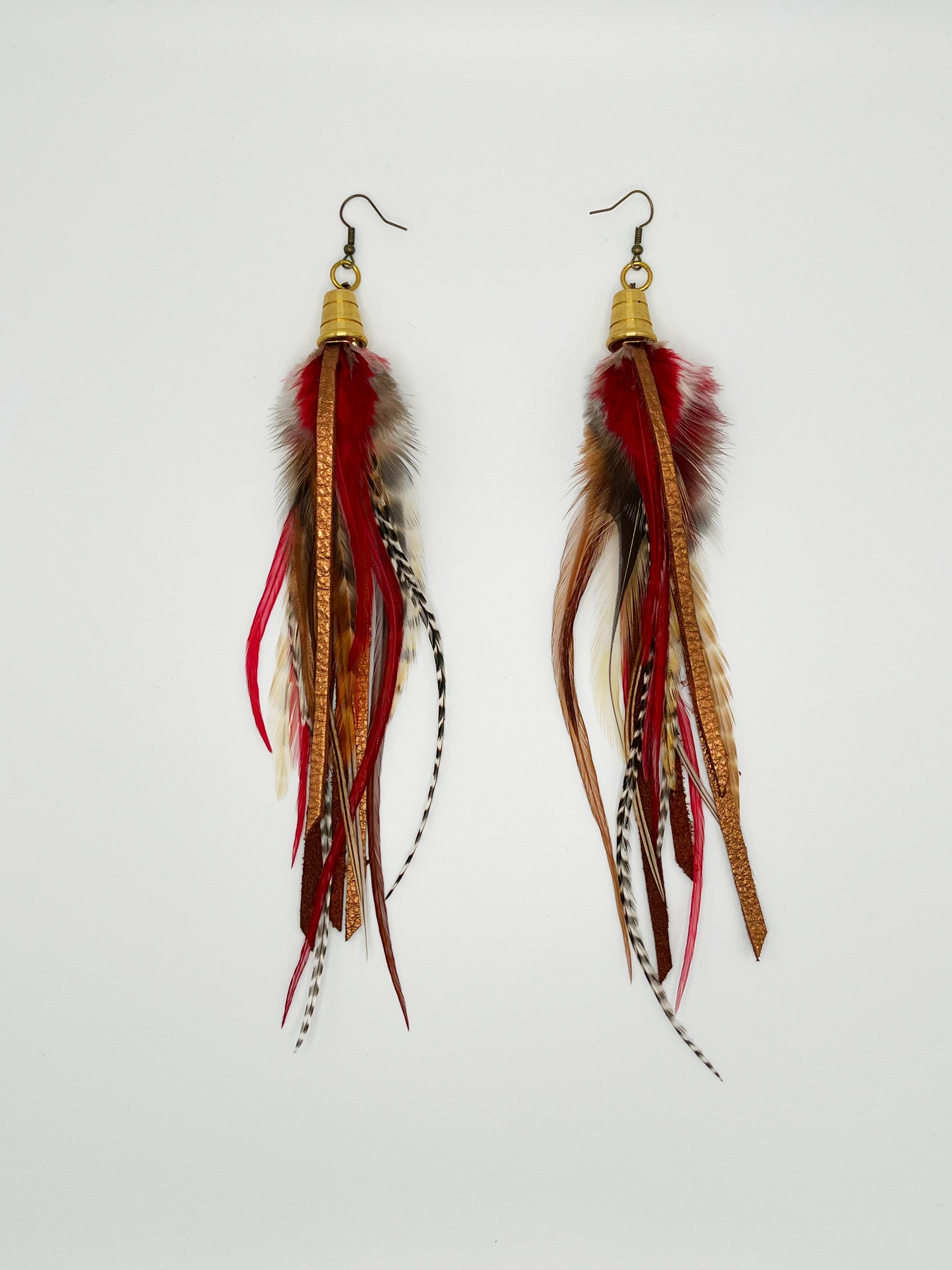 Long feather earrings in brown and deep red, with metallic bronze leather strips, hanging from a gold colored cap pendant.