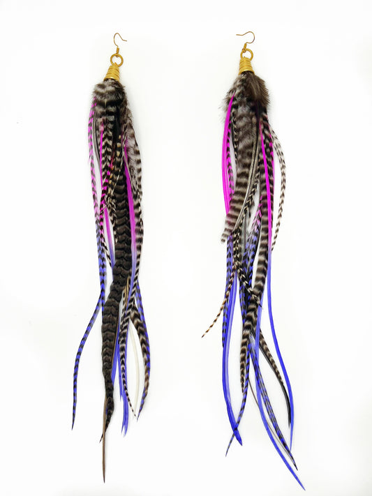 Extra  long feather earring in black, white, hot pink and purple. All feathers hang from beneath a gold pendant. 