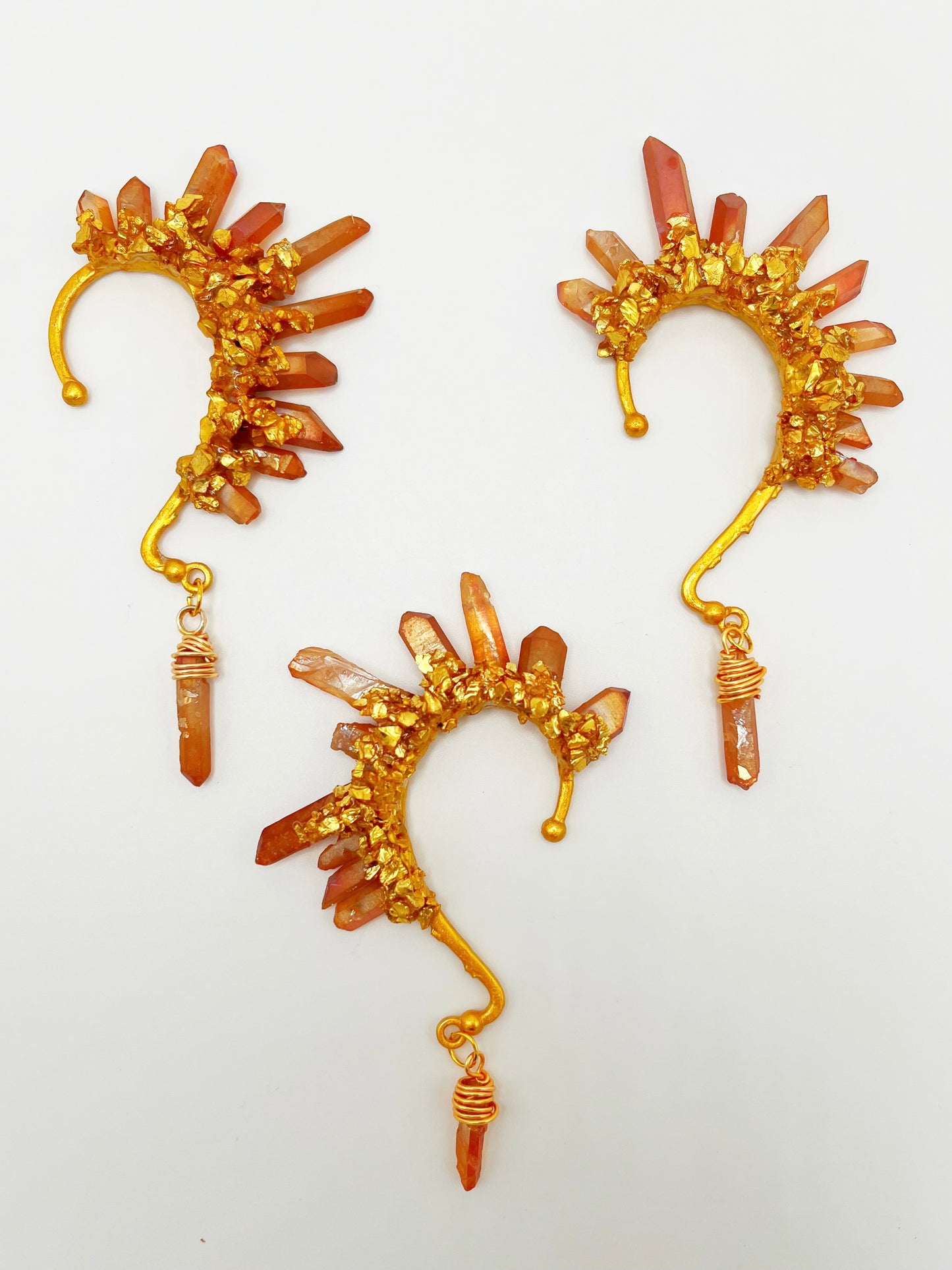 Three orange citrine crystal ear cuffs with crushed gold accents. A wire wrapped stone hangs from the bottom of each cuff. 