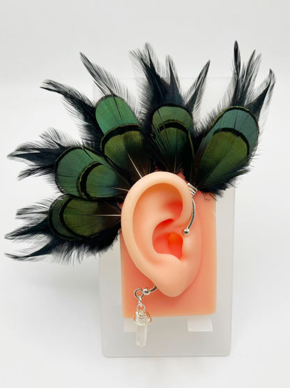 Black rooster and emerald green lady Amherst feather ear cuff, modeled on an ear. A wire wrapped quartz stone dangles from the bottom of the cuff behind the ear.