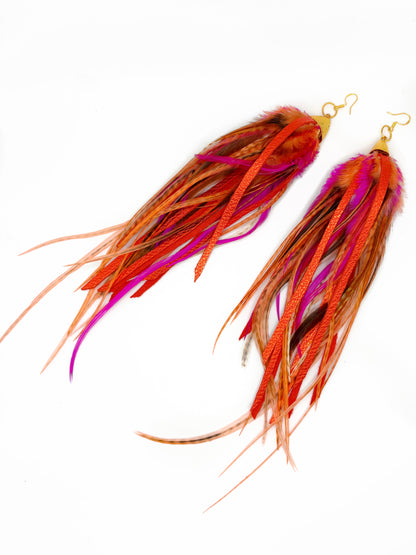 Two fishing lures with orange and pink feathers on a white background